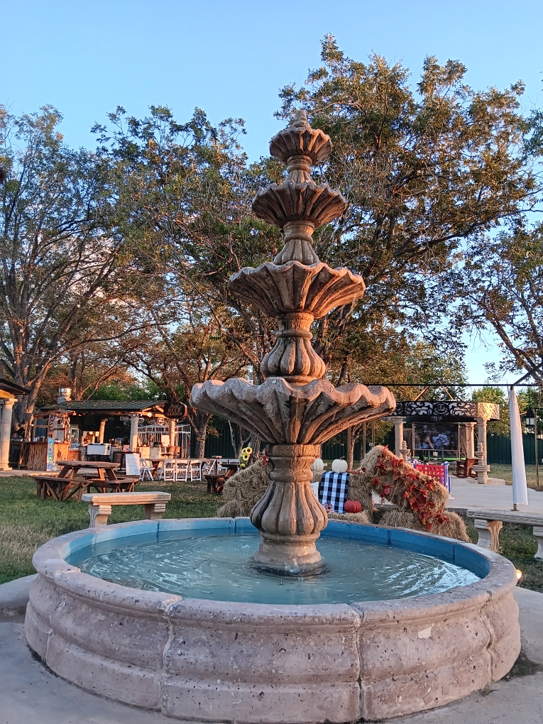 Stone tiered fountain surrounded by trees at golden hour